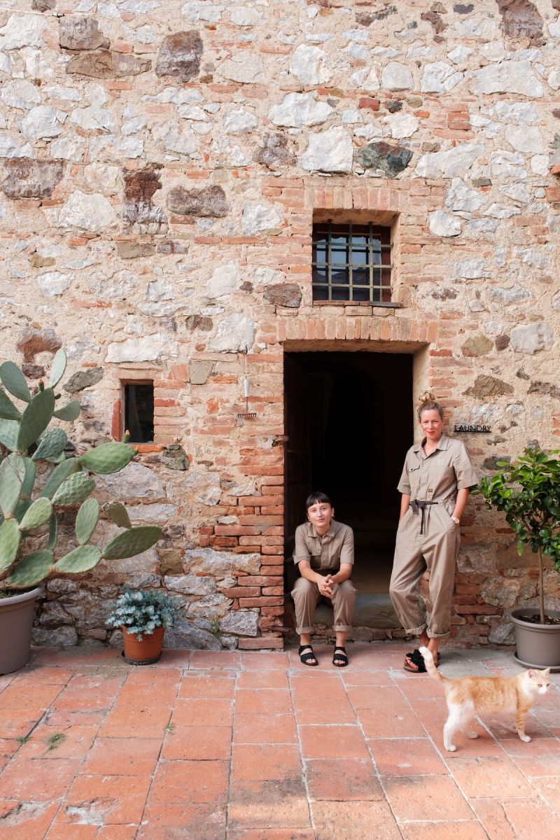 Architects and co-founders Nina Mair and Ana Turcan at the entrance to Colle ai Lecci borgo, Chianti Classico, Tuscany, outside the restored 1720 stone farmhouse with terracotta courtyard and resident cat