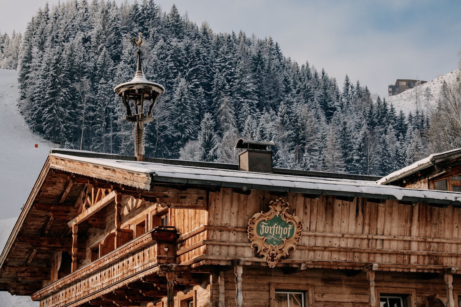 Larch-clad facade of Naturhotel Forsthofgut rising against the jagged limestone peaks of the Leogang Steinberge, the five-star forest hotel set into pine woodland in Leogang, Salzburger Land, Austria | The Aficionados.