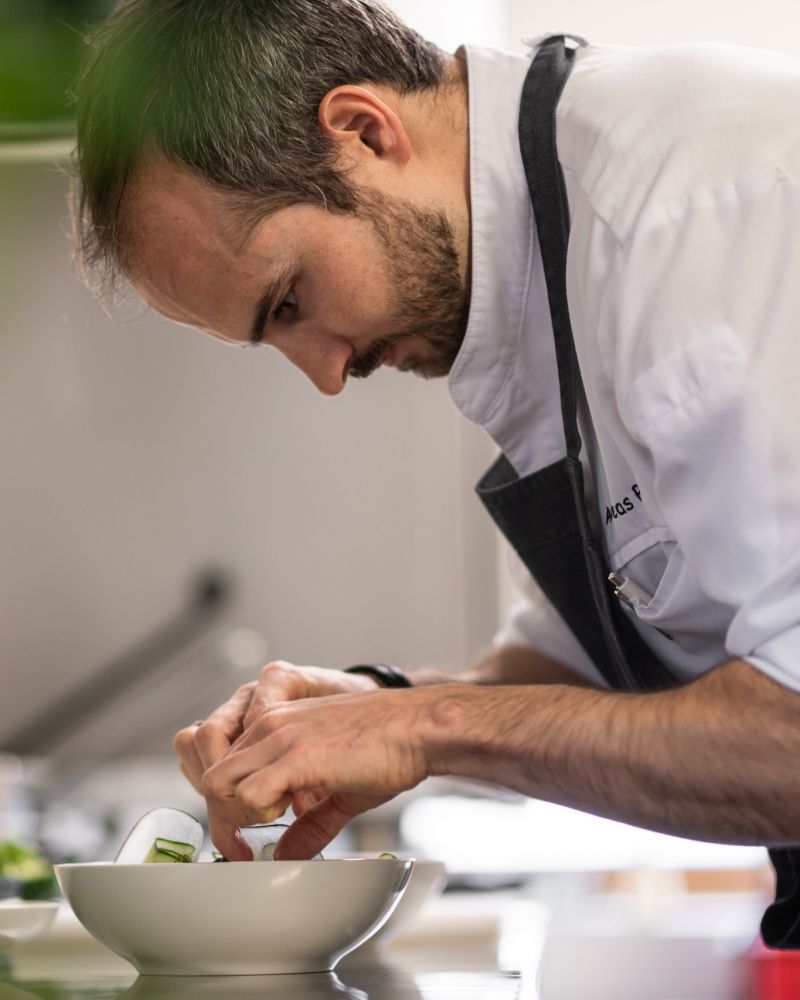Chef Andreas Pircher | Chef looking down at his food preparations| Hotel Schwarzschmied Best Wellness and Design Retreat in South Tyrol | The Aficionados 