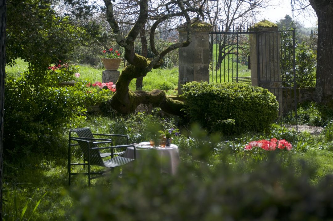Secret garden seating stone wall iron gates geranium flowers romantic outdoor space Maison Duroy grounds | The Aficionados