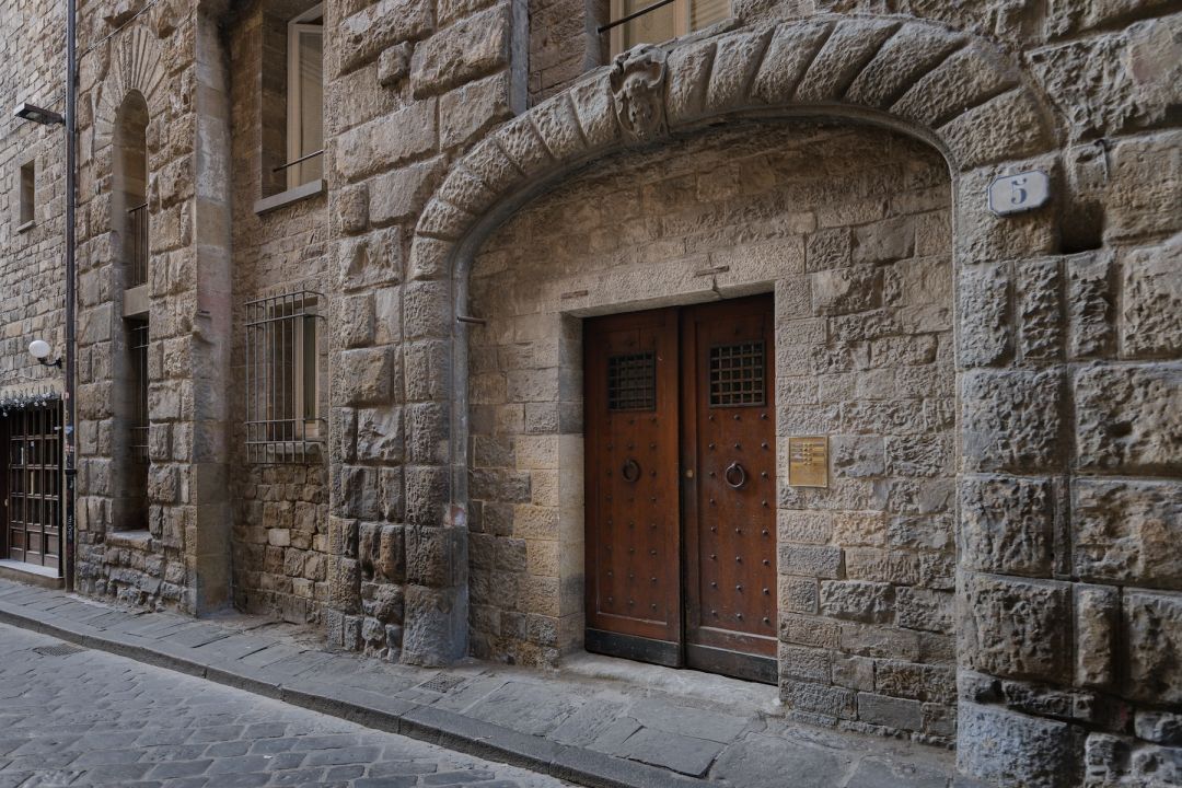 Studded wooden doors beneath a rusticated stone arch and carved shield at Via delle Terme 5, the street entrance to Terme Historical Tower, images © Tommaso Pini