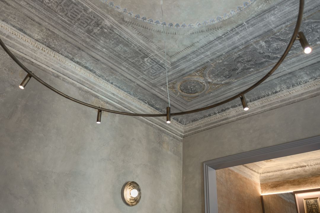 Restored grisaille ceiling with fret bands and a rosette above a bronze ring of spotlights, Medici Historical Home, images © Tommaso Pini