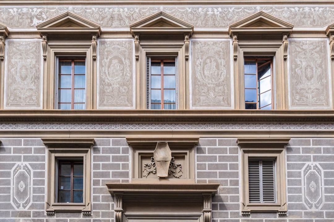 The sgraffito facade of Palazzo Lanfredini on Lungarno Guicciardini, Florence, panels of grotesques between pedimented windows above a ground floor scored into mock stone blocks, a carved coat of arms over the door. © Tommaso Pini