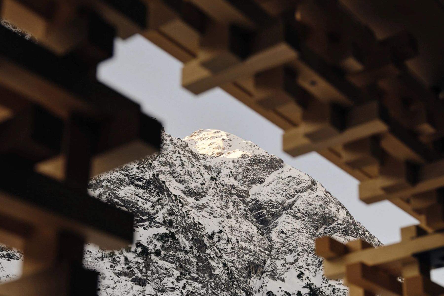 Snow-covered peak above Lech framed by the open timber lattice of Shinichiro Ogata's screen at Haus W in Zug.