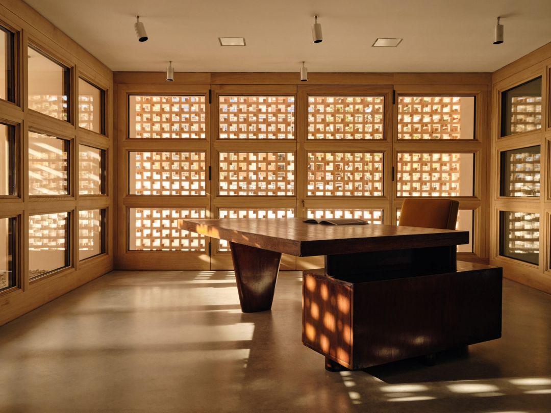 The Werkraum Zug workspace at Haus W, a dark timber table on a polished concrete floor with Ogata's lattice screen filling the windows behind.