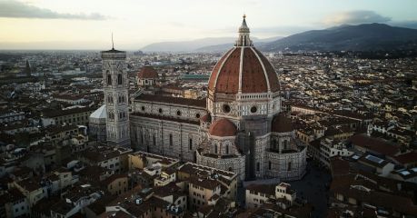 Aerial view of Florence at dusk, Brunelleschi’s terracotta dome crowning the cathedral of Santa Maria del Fiore beside Giotto’s campanile, the city’s roofs stretching to the Tuscan hills.
