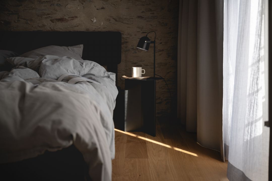 Robuust Amsterdam bed frame with grey linen, exposed stone wall and black bedside lamp — boutique holiday apartment interior, Klara Rooms, Trittenheim Moselle | The Aficionados
