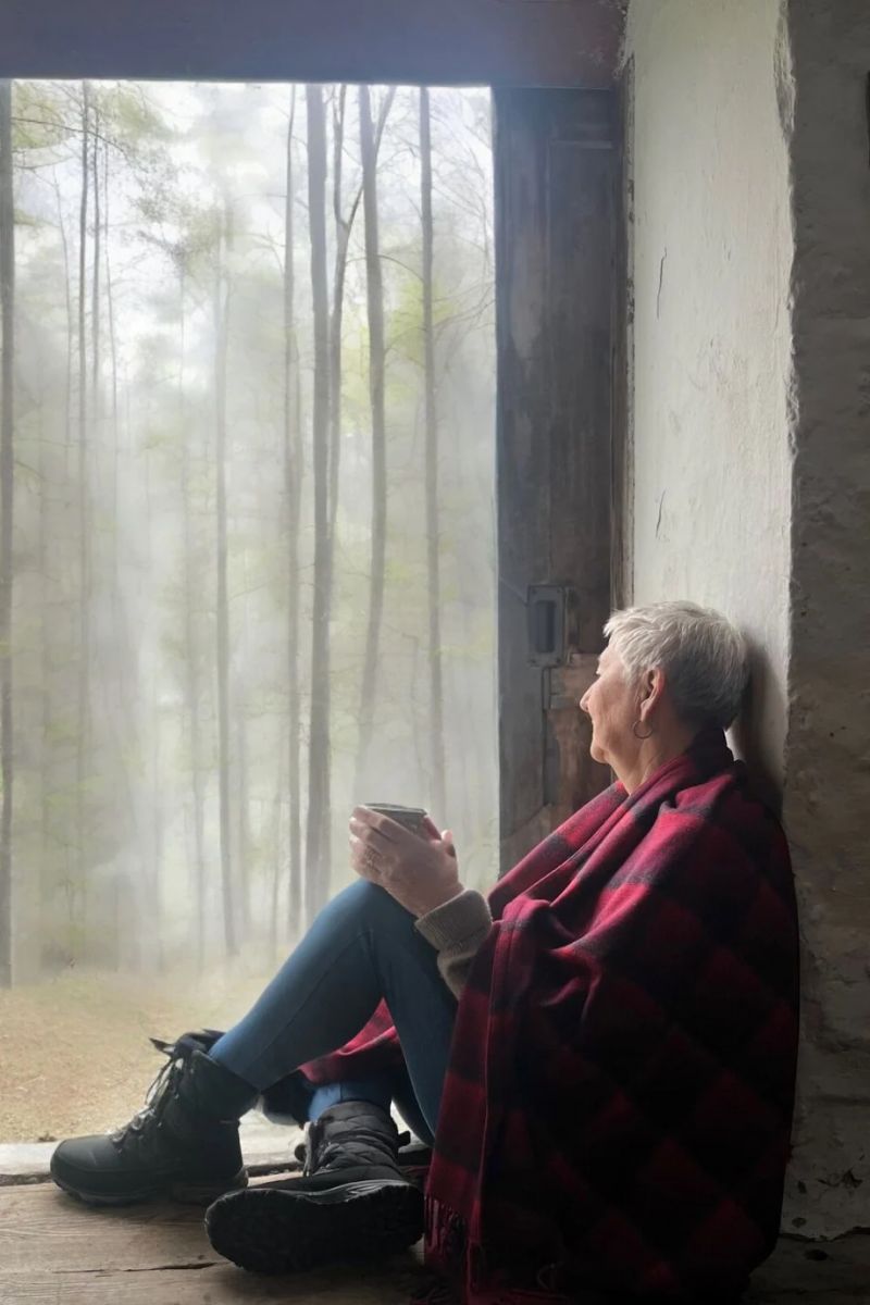 Person sitting looking at the Pembrokshire coast wrapped in a blanket | Melin Tregwynt | Artisan Blankets Woven in Wales - A British Hertiage Brand | TheAficionados.com