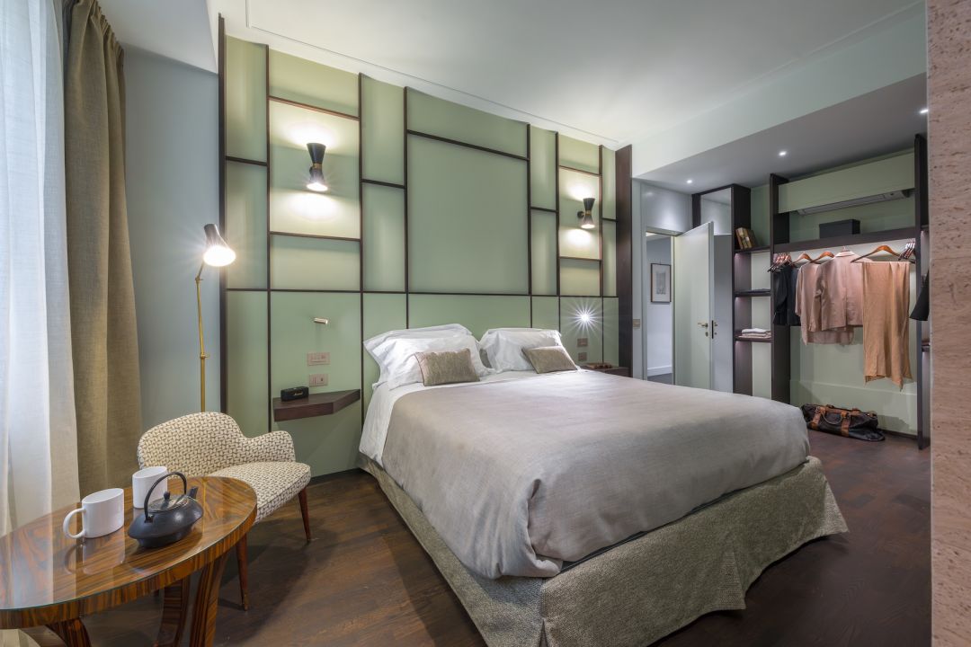 Principal suite in sage, its headboard wall gridded with dark wood battens, black cone wall lights and a macassar ebony table set for tea, Ponte Vecchio Panorama, images © Tommaso Pini