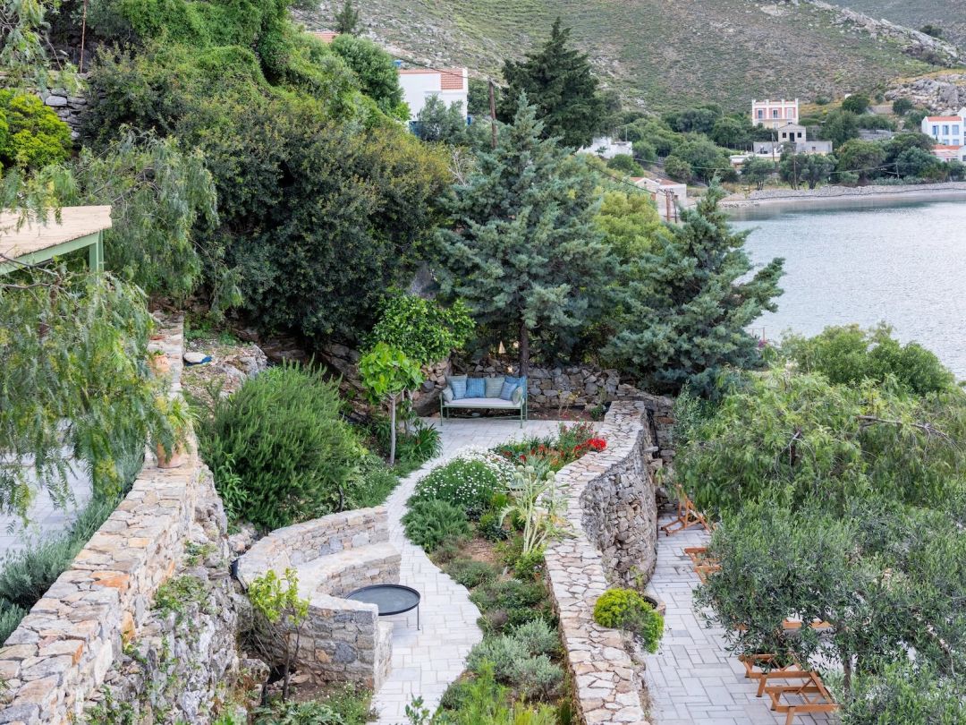 Terraced gardens by Dimitri Launder, at The Selene, Symi: curving dry-stone walls, pale stone paths and drought-resistant planting above Nimborio Bay. |Photo ©️ Will Slater