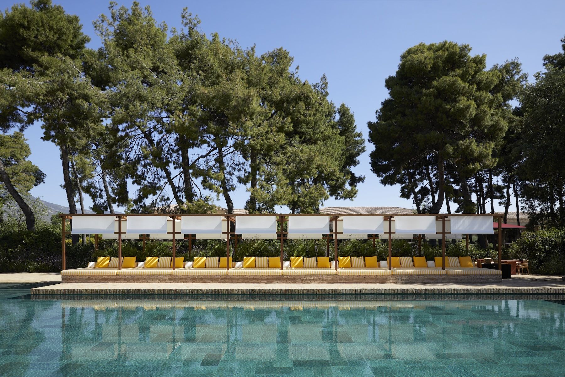 Poolside daybeds with striped cushions under a timber pergola at TATOÏ Club Athens | The Aficionados.com