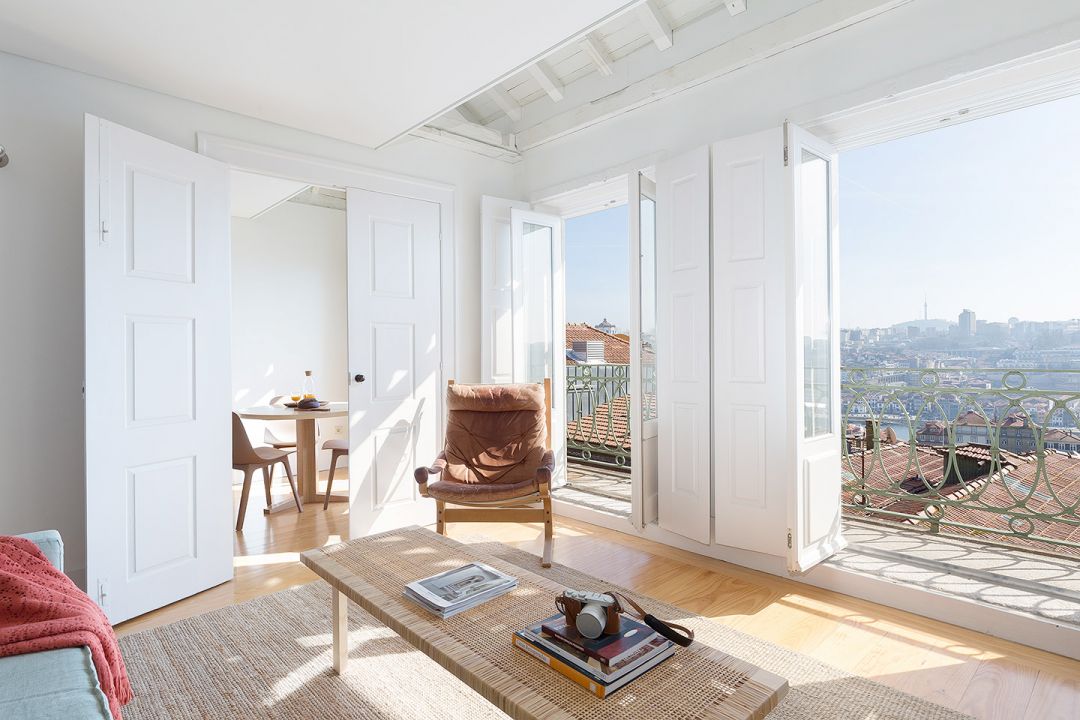Sunlit living room at B28 Apartments Porto with a vintage Scandinavian leather chair, original carved-wood panelled doors and a balcony over the old Jewish quarter.| The Aficionados 