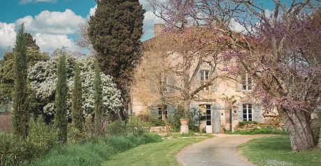 Maison Duroy exterior spring view pink Judas tree blooms honeyed stone facade vert de gris shutters Gascogne countryside | The Aficionados