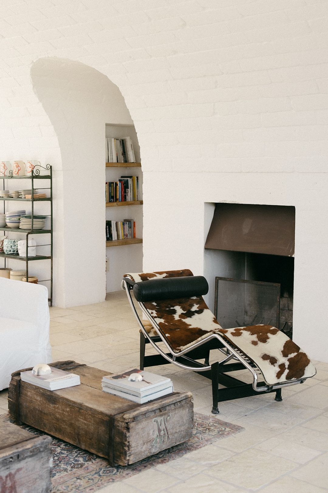 Le Corbusier LC4 chaise in cowhide beside the fireplace, with a salvaged timber chest and chianca limestone floor in the living room at Masseria Moroseta, Ostuni, Puglia | The Aficionados.