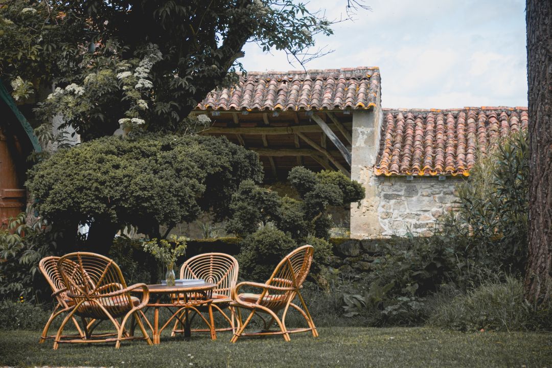 Secret garden seating stone wall iron gates geranium flowers romantic outdoor space Maison Duroy grounds | The Aficionados