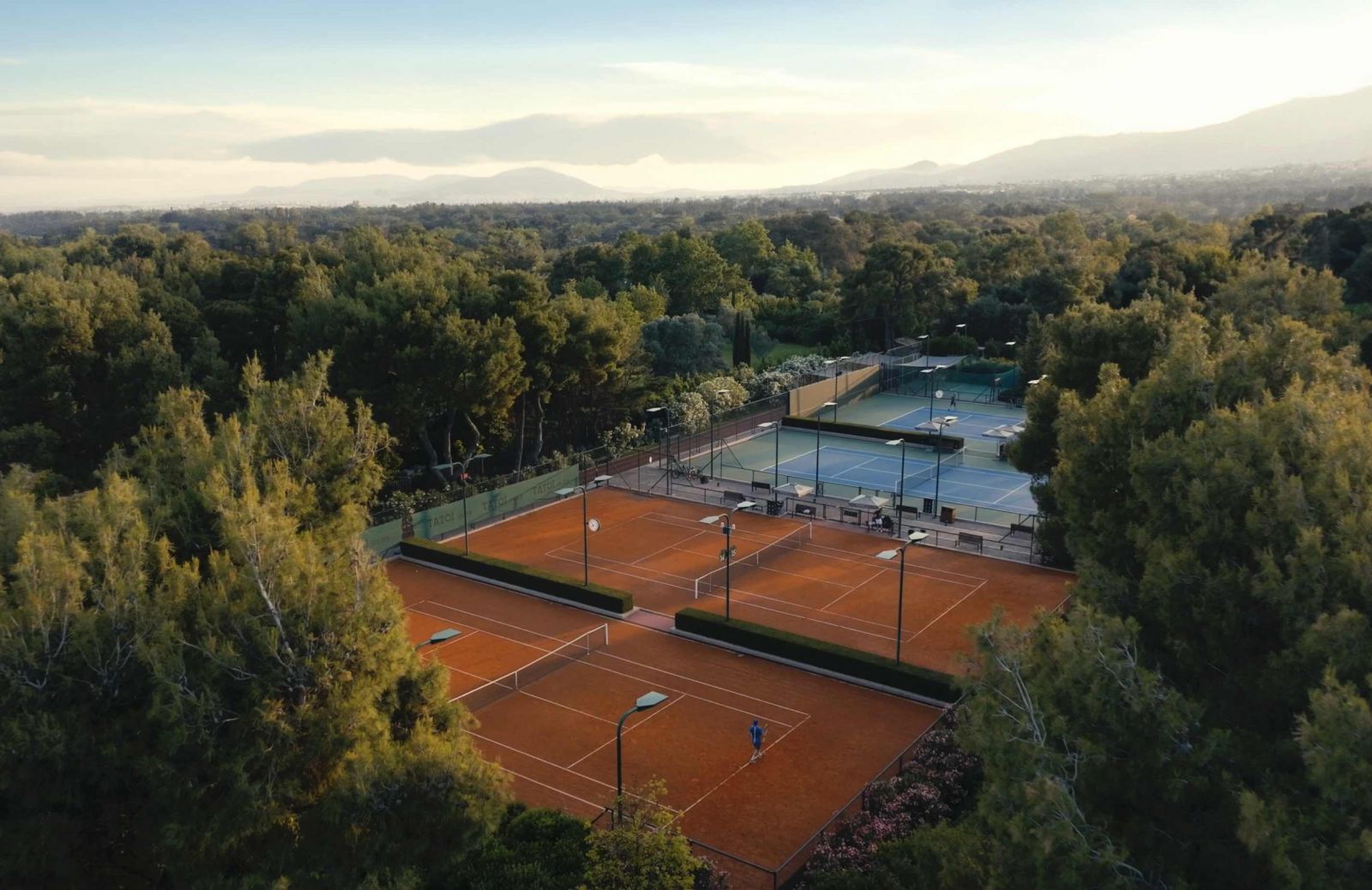 Aerial view of clay tennis courts in the pine forest at TATOÏ Club Athens | The Aficionados.com