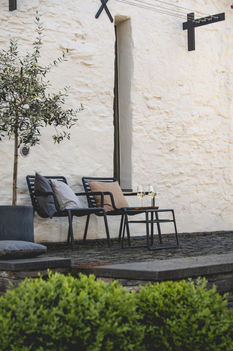 White lime-rendered wall with black steel trellis, olive tree and village street lamp — Klara Rooms historic guesthouse exterior, Trittenheim, Moselle Valley Germany