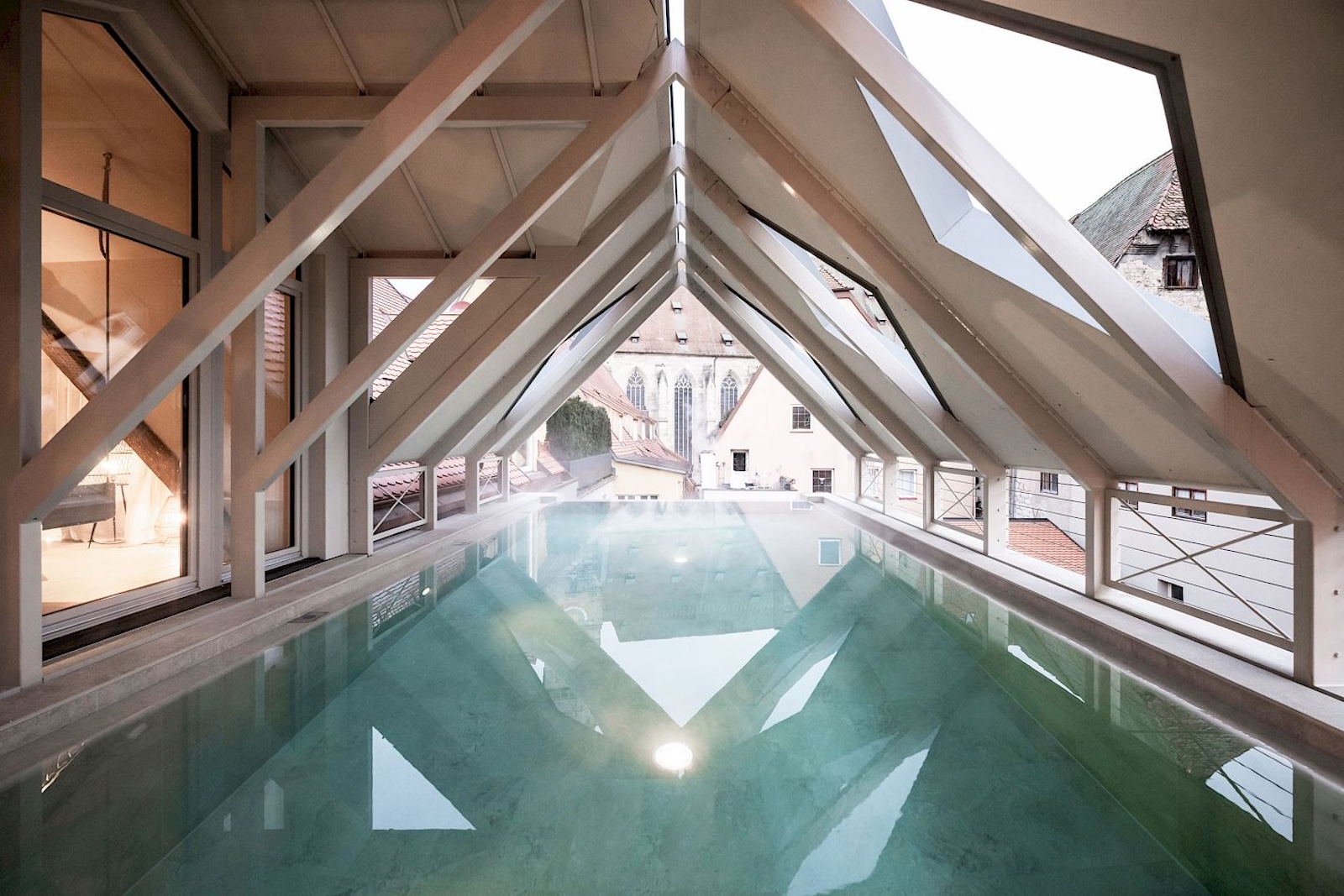 amazing rooftop pool housed within centuries old vaulted ceilings atop the Goldener Rose Boutique Hotel designed by NOA architecs | blue swimming pool, open viewpoints cut into the roofline | Dinkelsbühl Bavaria: Design, Boutique Hotels and Travel Guide