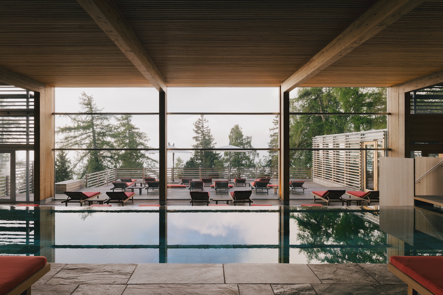 Architecturally designed hotel swimming pool with large plate glass Critall windows looking outwards across the Alps and forests. | 