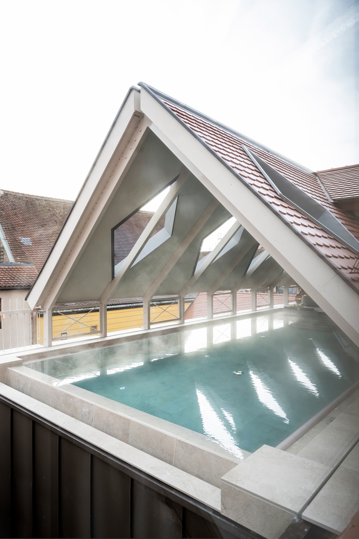 Arched structure over a swimming pool = architectural detailing | Goldene Rose Dinkelsbühl by NOA | Rooftop Spa and Heritage Hotel Restoration