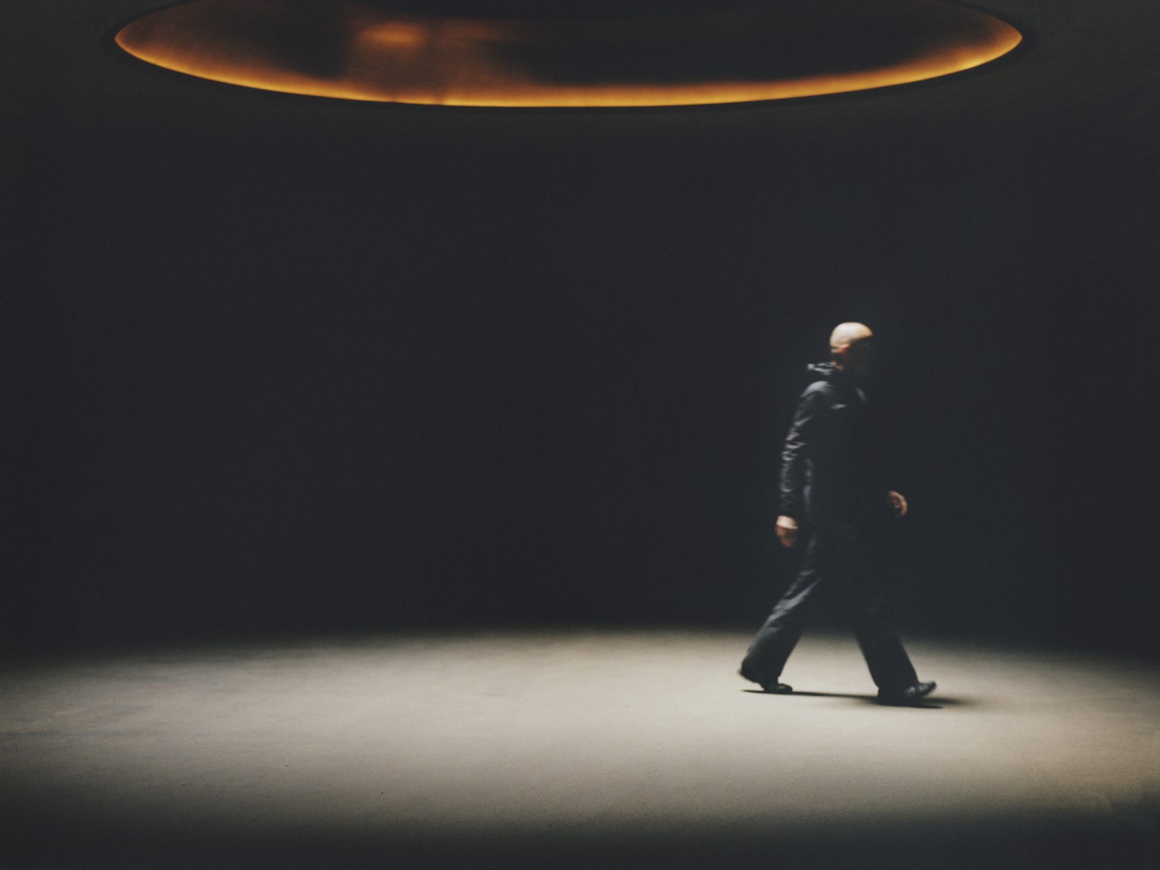 A figure crossing the Almhof Schneider garage in Lech beneath Shinichiro Ogata’s glowing oval light | The Aficionados