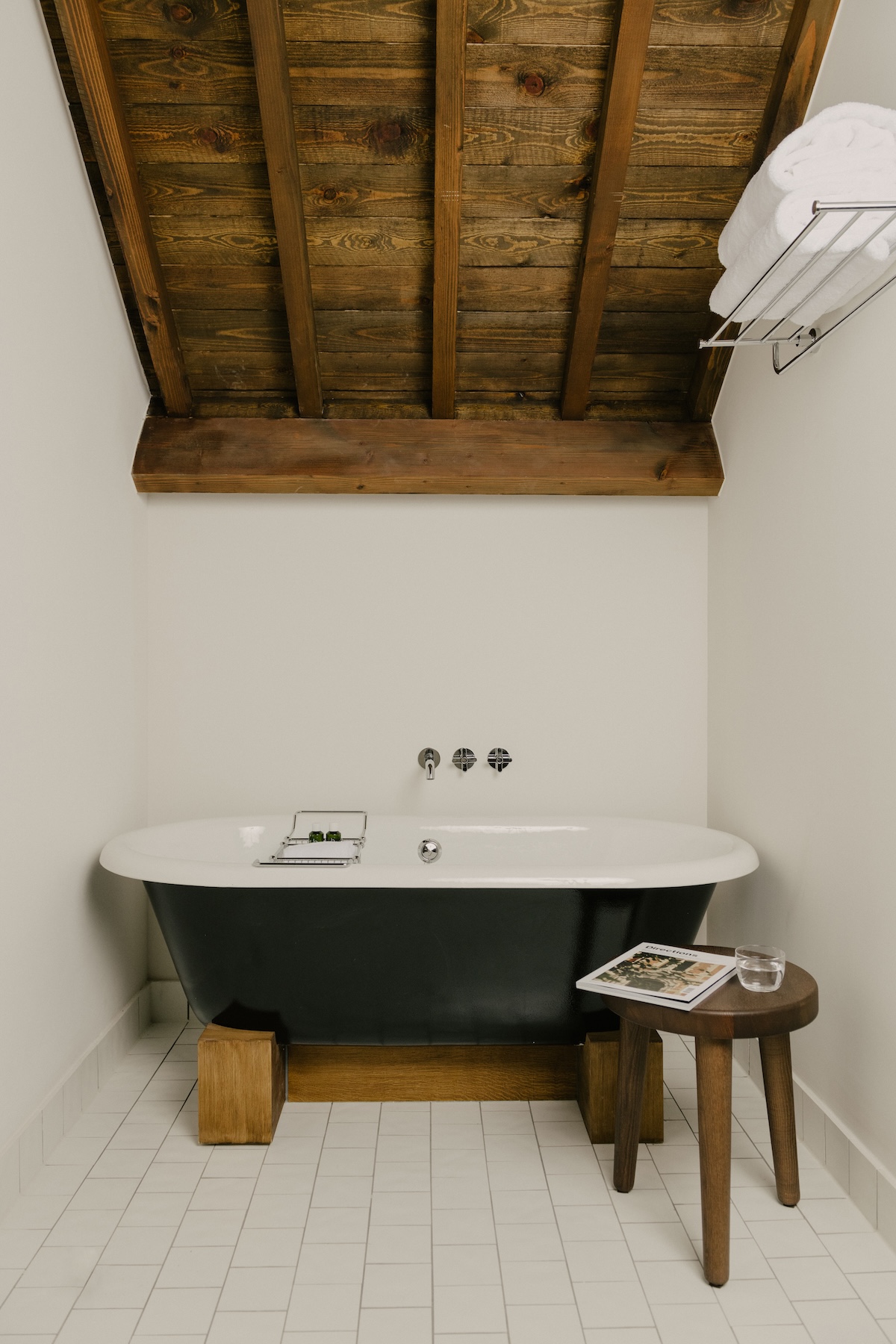 Freestanding black bathtub beneath timber roof rafters at Hotel Julien, Antwerp | The Aficionados