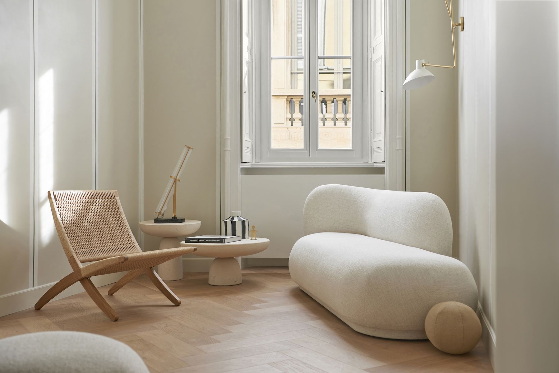 Crossing Condotti Milano | Minimalist Milanese townhouse interior in soft cream tones with a woven lounge chair and design furniture