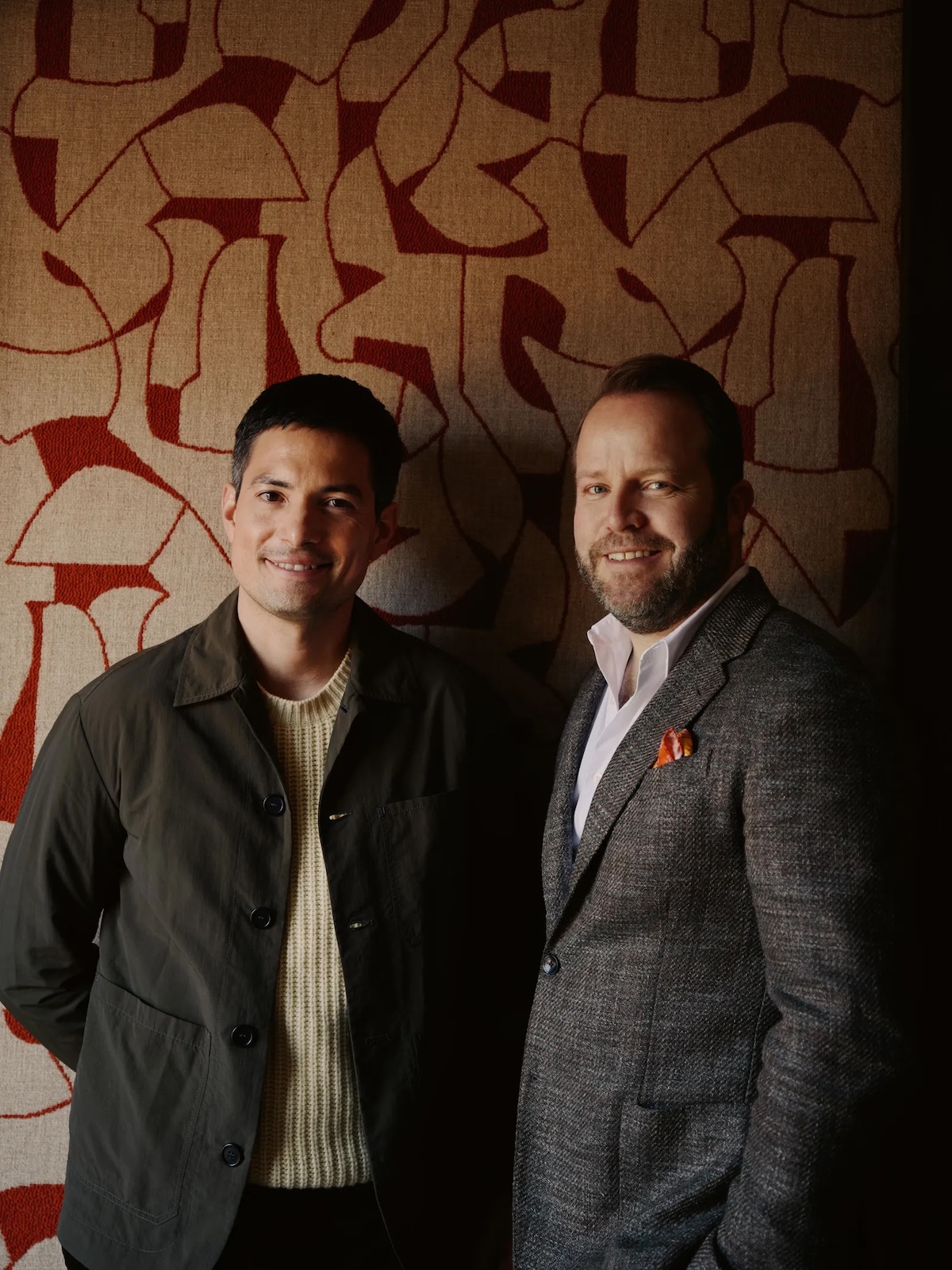 Benny Schnieider and partner Patrik | Tow men stnading against a floral wallpaper in traditional cloth suits | Hotel Arlberg Lech, Austria | Manmade: 12 Hotels Shaped by Men of Design and Style