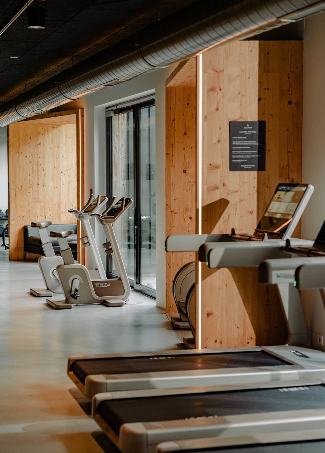The 300 m² waldSPA Fitness floor at Naturhotel Forsthofgut, spruce-clad walls lined with Technogym bikes and treadmills, the 24-hour gym in Leogang, Salzburger Land, Austria | The Aficionados.