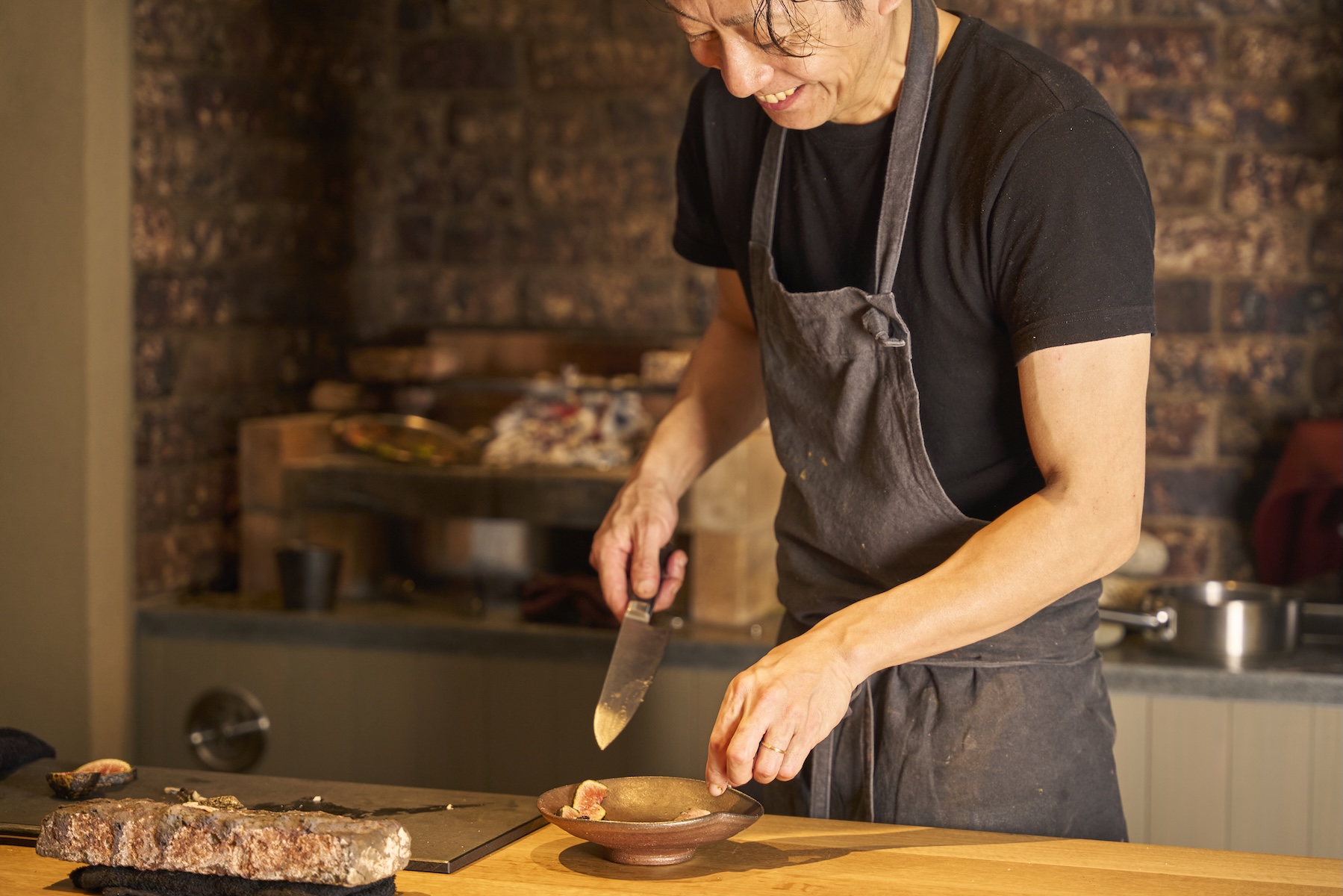 Chef Makoto Fuse slicing fresh figs into a stoneware bowl at the counter of Auberge Né, Niigata | The Aficionados