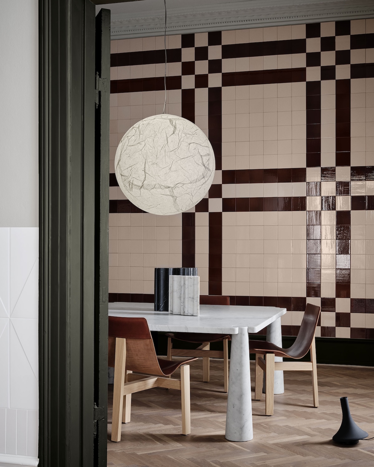 Angelo Mangiarotti dining setting in Artistic Position in Space: white Carrara marble Eros table with leather Tre 3 chairs and marble vases, against a checkerboard File Under Pop tiled wall.