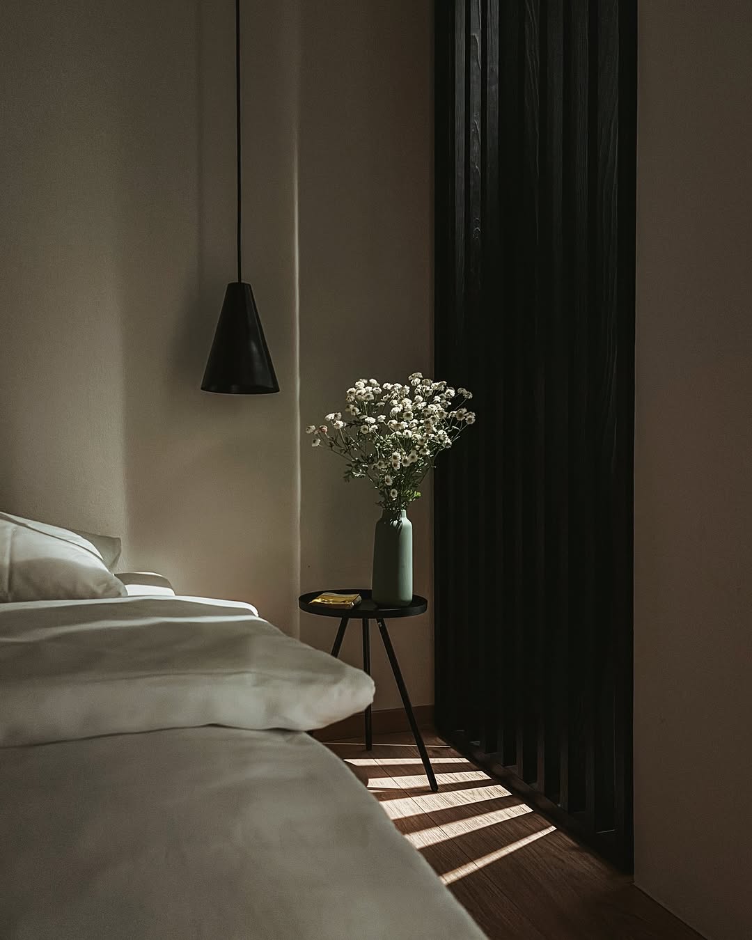 Cool contemporoary bedroom interiors in subtle greys  pendand light and white panelled walls |Raw Heritage Retreats: Design-Led Hideaways & Nature Sanctuaries Across Europe