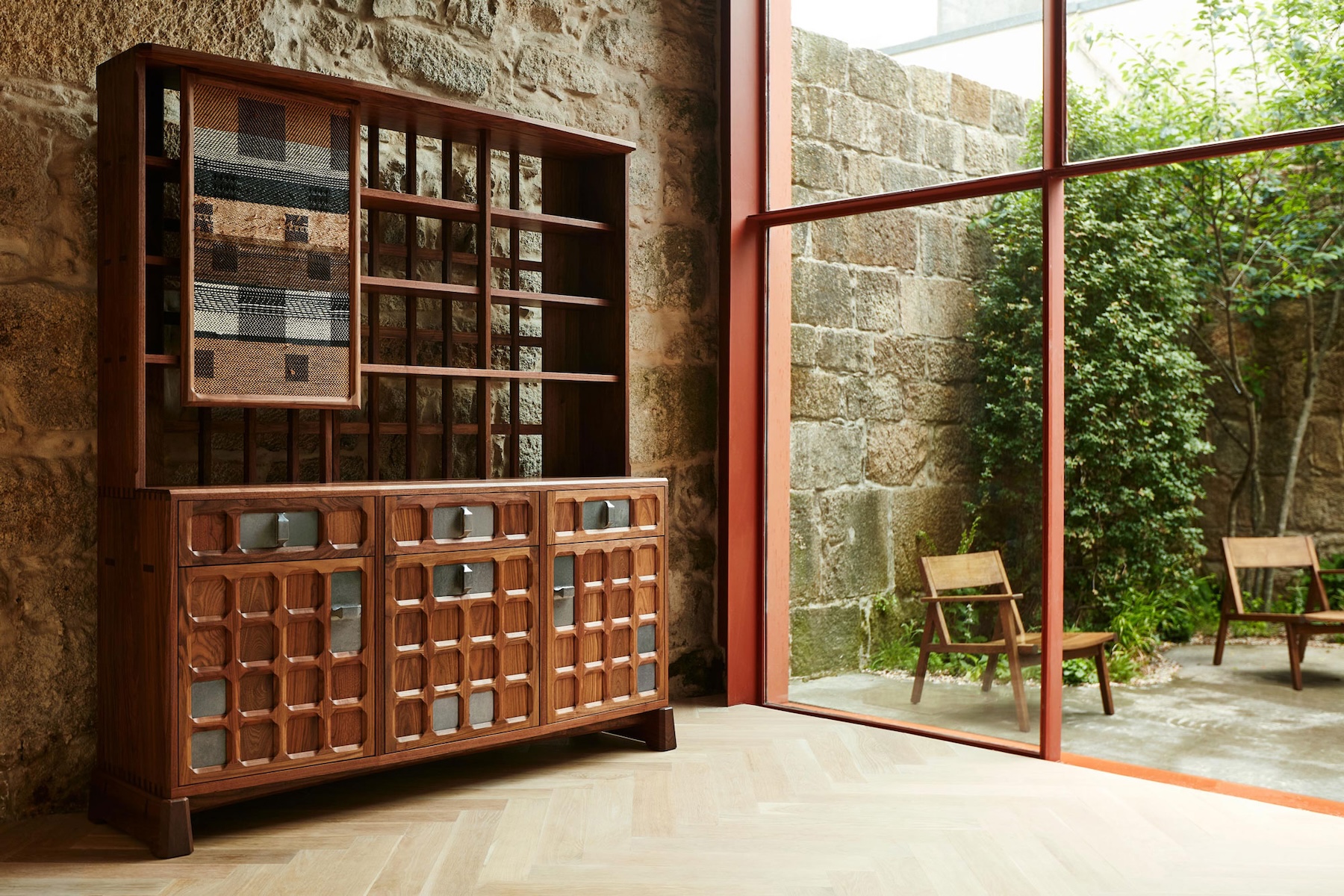 Solid walnut dresser with woven panel and carved door fronts beside a courtyard window at De La Espada | The Aficionados