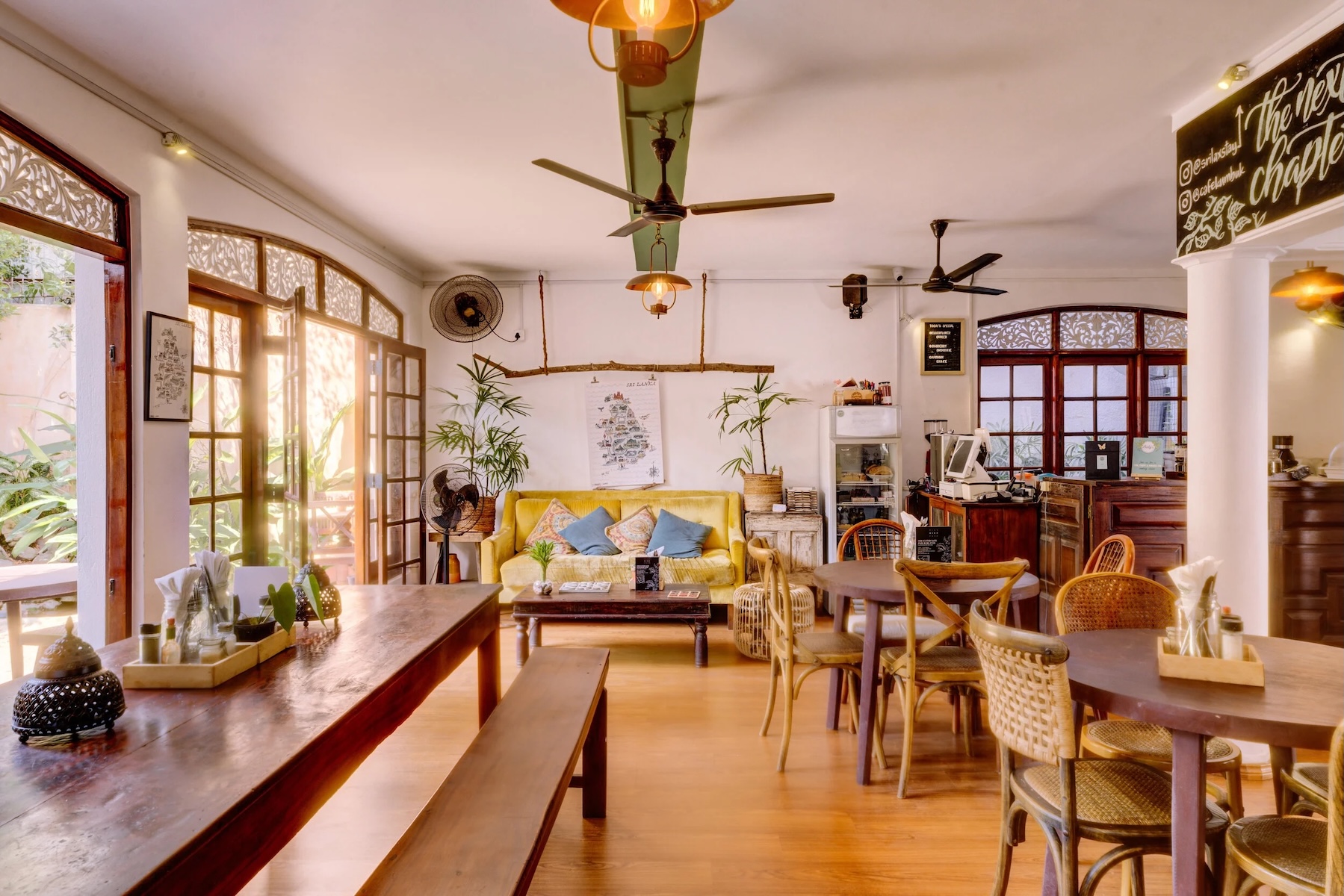 Sunlit café interior with rattan chairs, ceiling fans and timber tables at the Paradise Road Gallery Café, Colombo