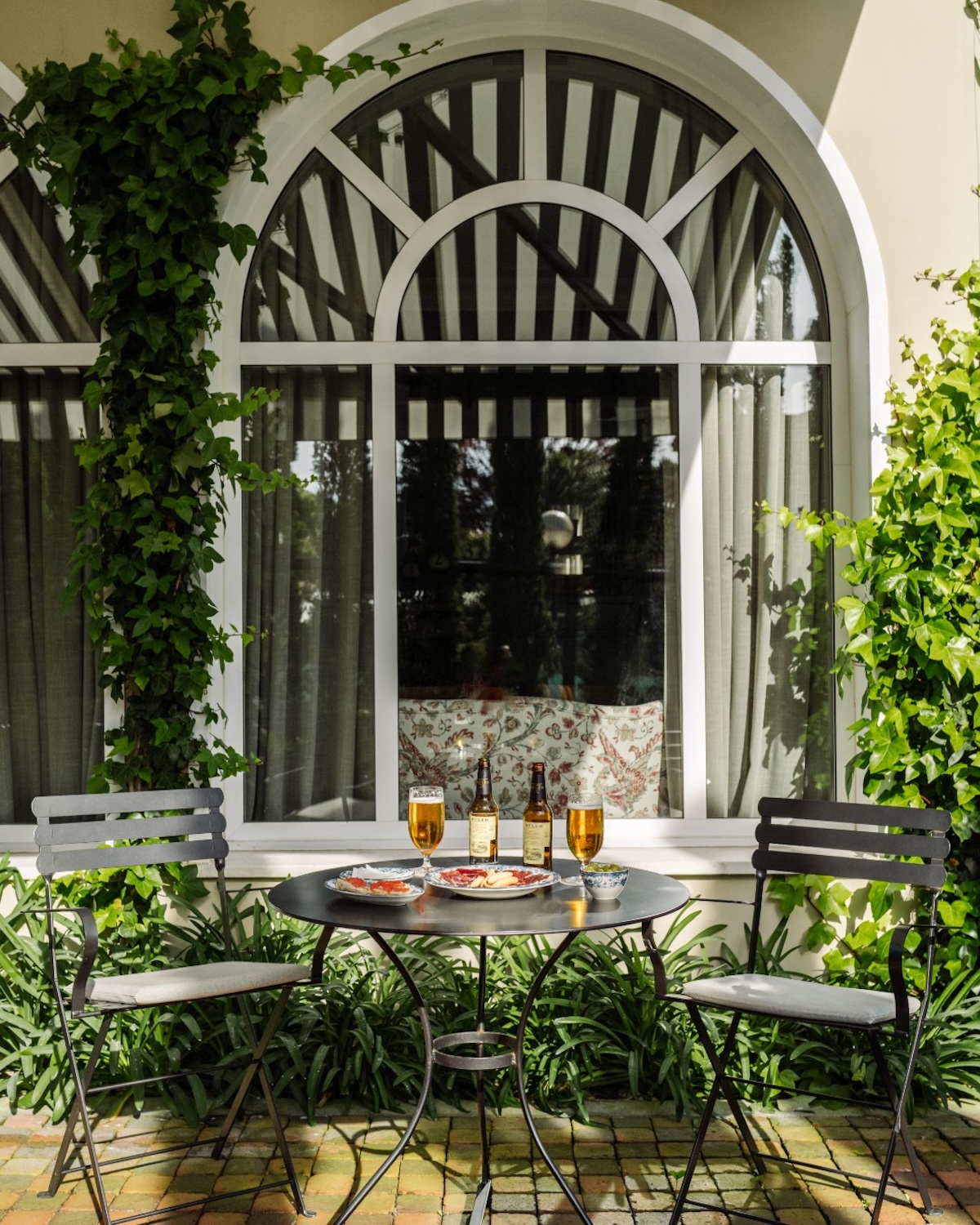 Private terrace at Villa Soro laid with beer and pintxos beneath an ivy-framed arched window | The Aficionados