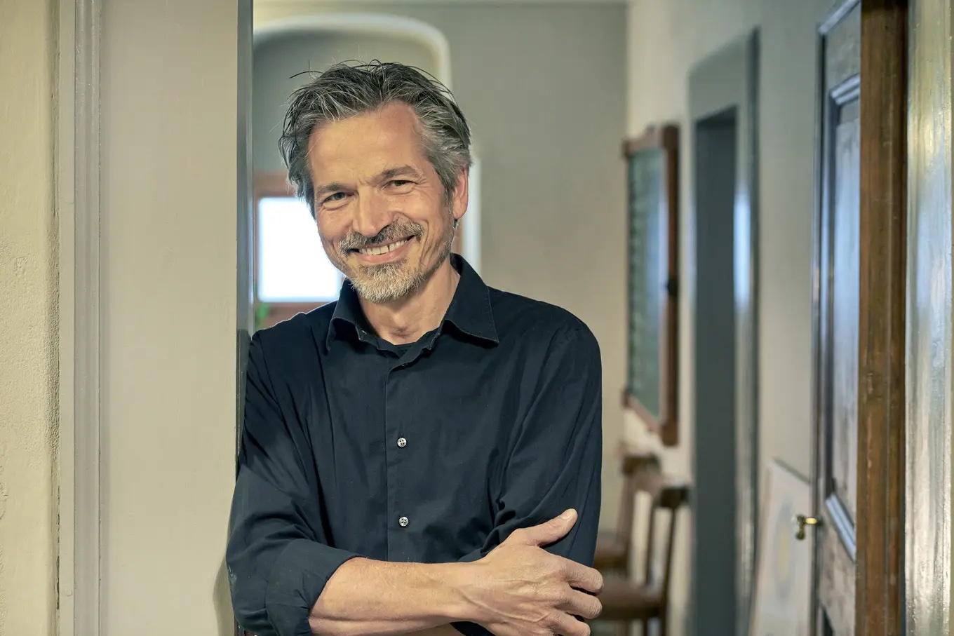 Daniel Erne owner fo the Pontisella Gueshouse Hotel in Switzerland, man smailing leangin against a doorway | Manmade: 12 Hotels Shaped by Men of Design and Style