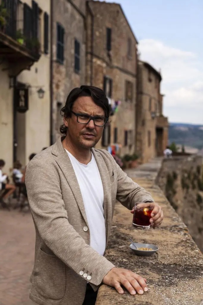John Voigtman owner creator of La Bandita Tuscany standing with a Negroni in hand overlooking the valley of Peinza | Manmade: 12 Hotels Shaped by Men of Design and Style