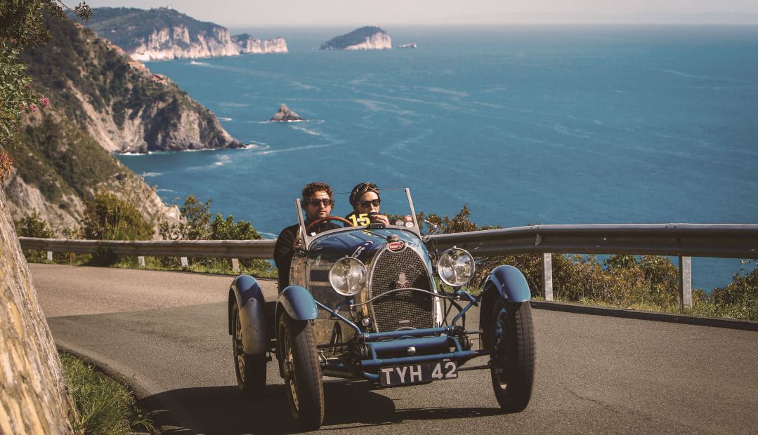 Classic motor car hugging the curve clifftop, sea background | Stylish Travel to Italy: Boutique Hotels, Design Stays & Culture