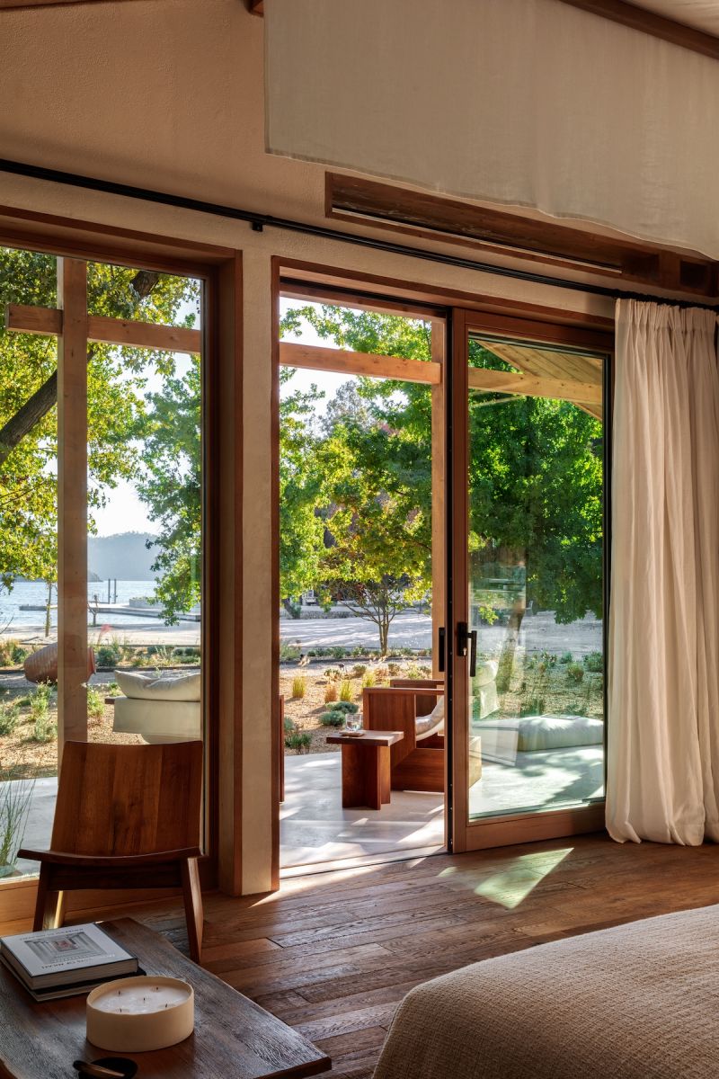 A timber-framed guest room at AHÃMA on Turkey's Günlüklü Bay, sliding doors opening to a garden and a glimpse of the sea beyond.