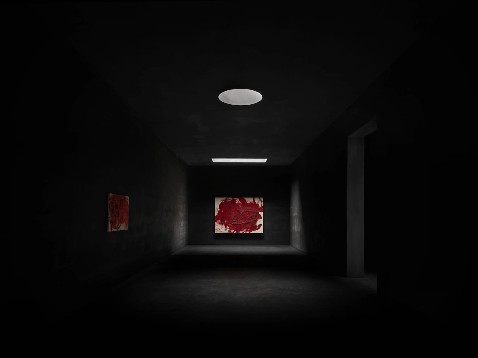 Red paintings by Kazuo Shiraga in a dark gallery beneath a skylight at Kanaal, Wijnegem | The Aficionados