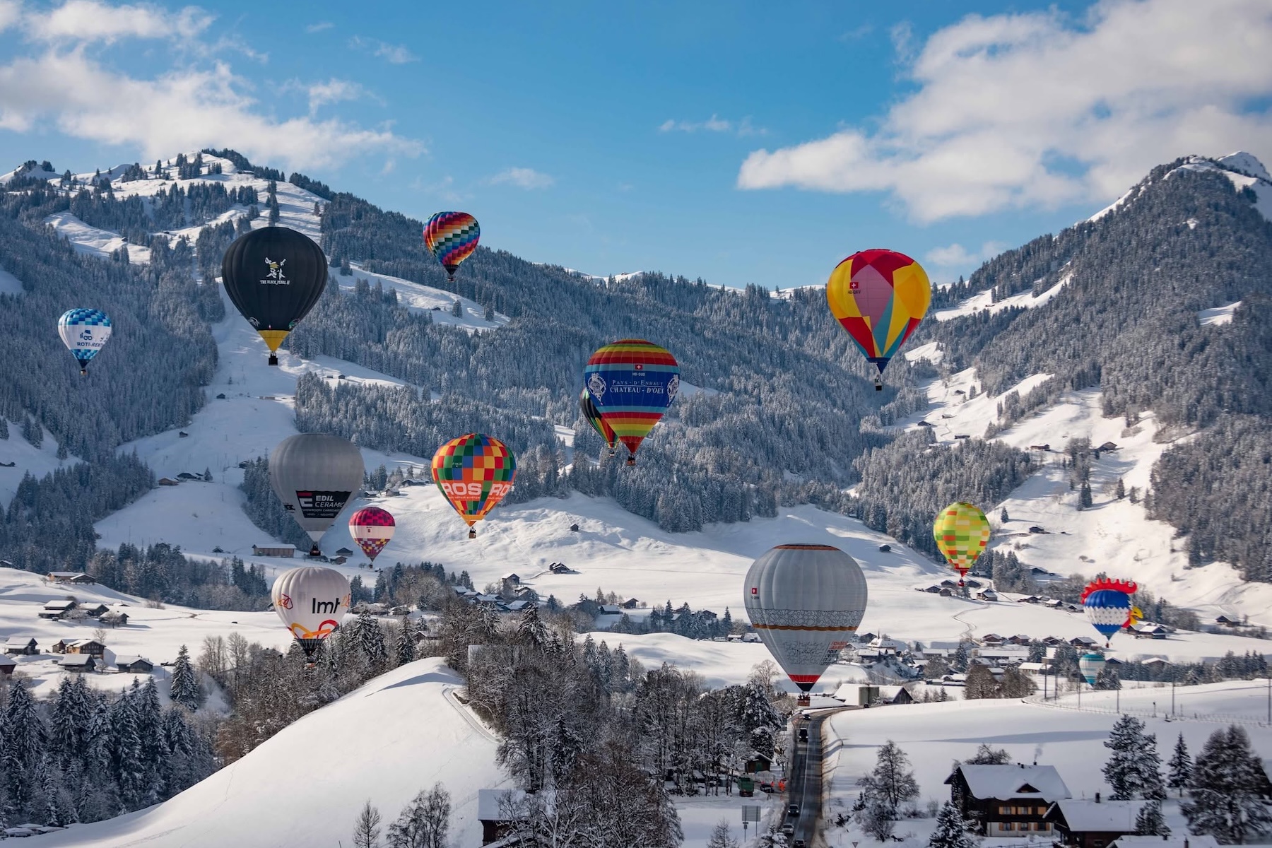 A colourful photo of Switzerland's famous hot air balloon festival, blue sky and balloons in it