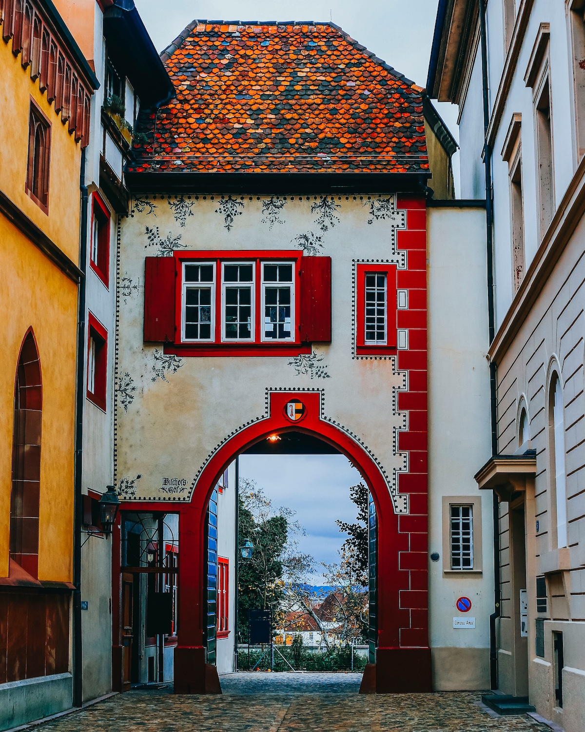 Historic Houses in Europe, here an arch leads through under a timber frame medieval house painted in red | Basel Travel Guide: Art, Architecture and Cultural Depth at the Heart of Europe | The Aficionados 