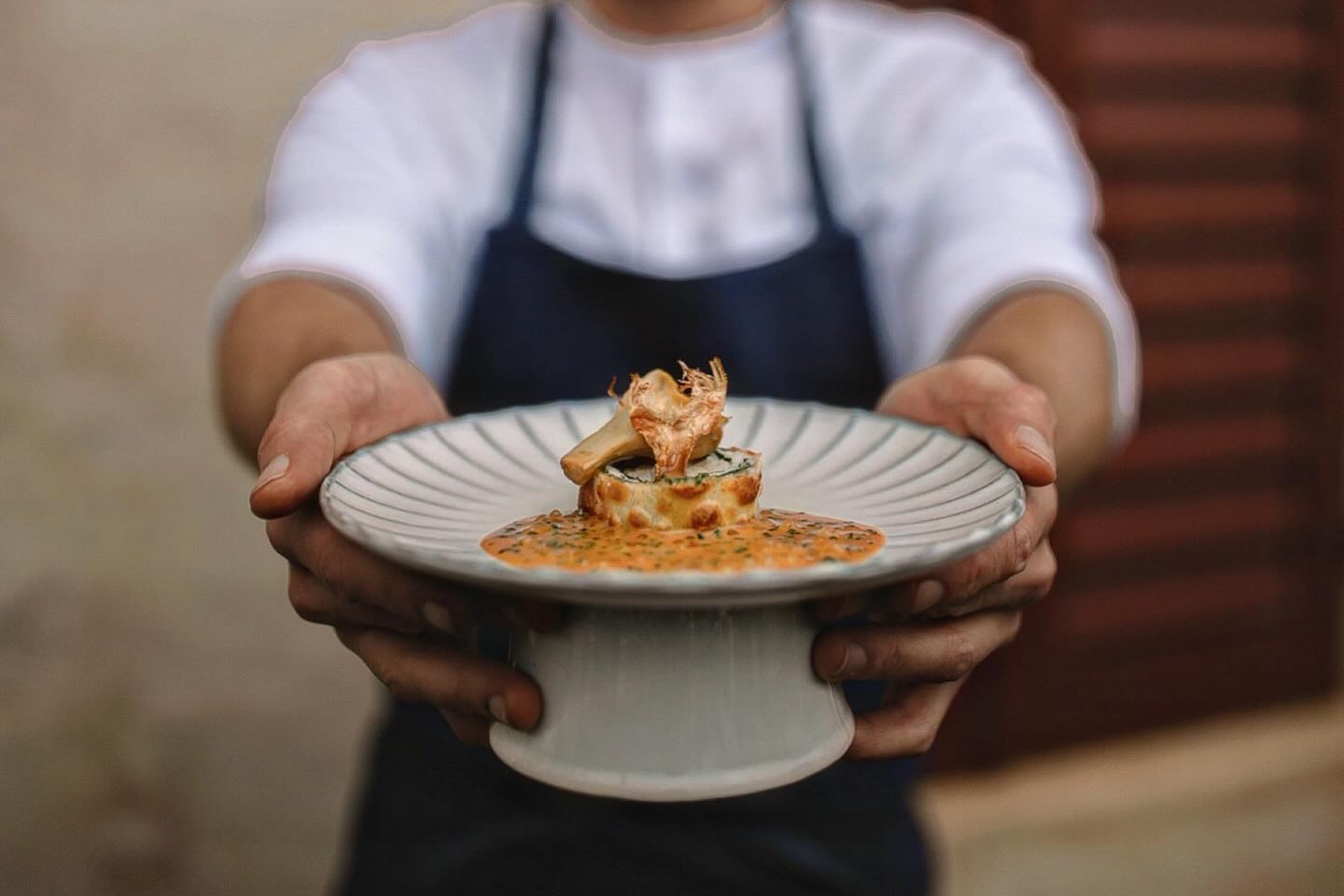 An opening course arriving in a hand-thrown stoneware bowl on cream linen at Christoph Huber's Blaue Traube, Lagundo | TheAficionados.com