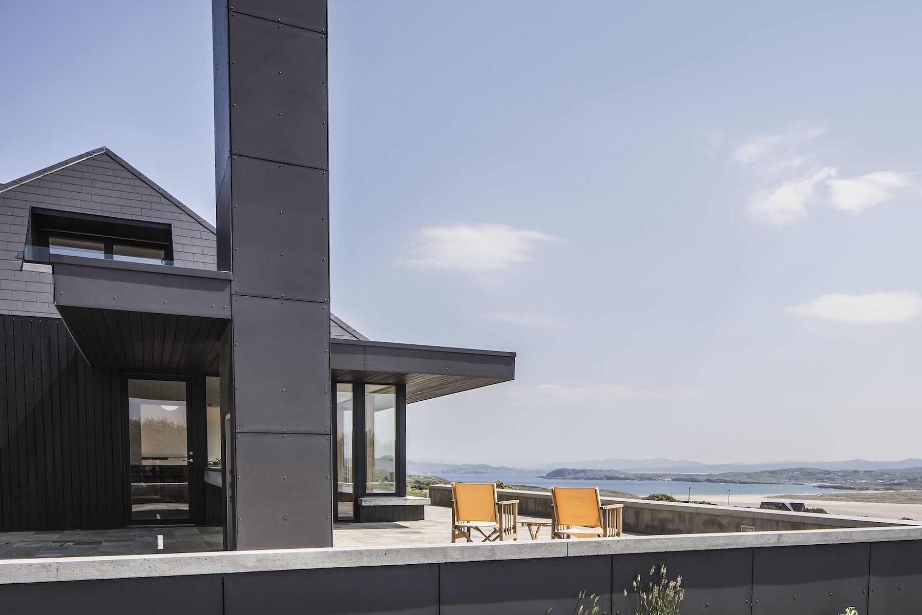 Breac.House Blackened larch and slate elevation with terrace above Sheephaven Bay, by MacGabhann Architects | Breac.House, Horn Head, Donegal, Ireland | The Aficionados