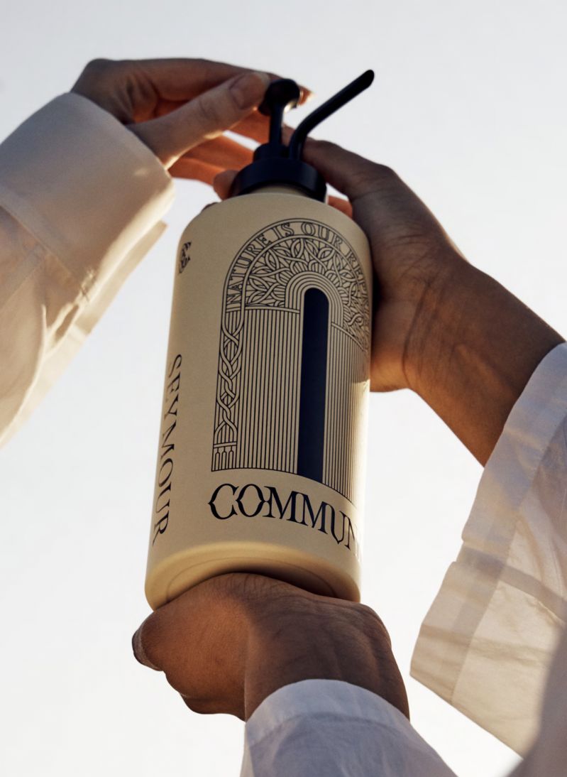 Commune Botanicals Seymour body wash in a refillable recyclable aluminium bottle held up to the sky, 99 per cent naturally derived sustainable self-care made in the UK | The Aficionados