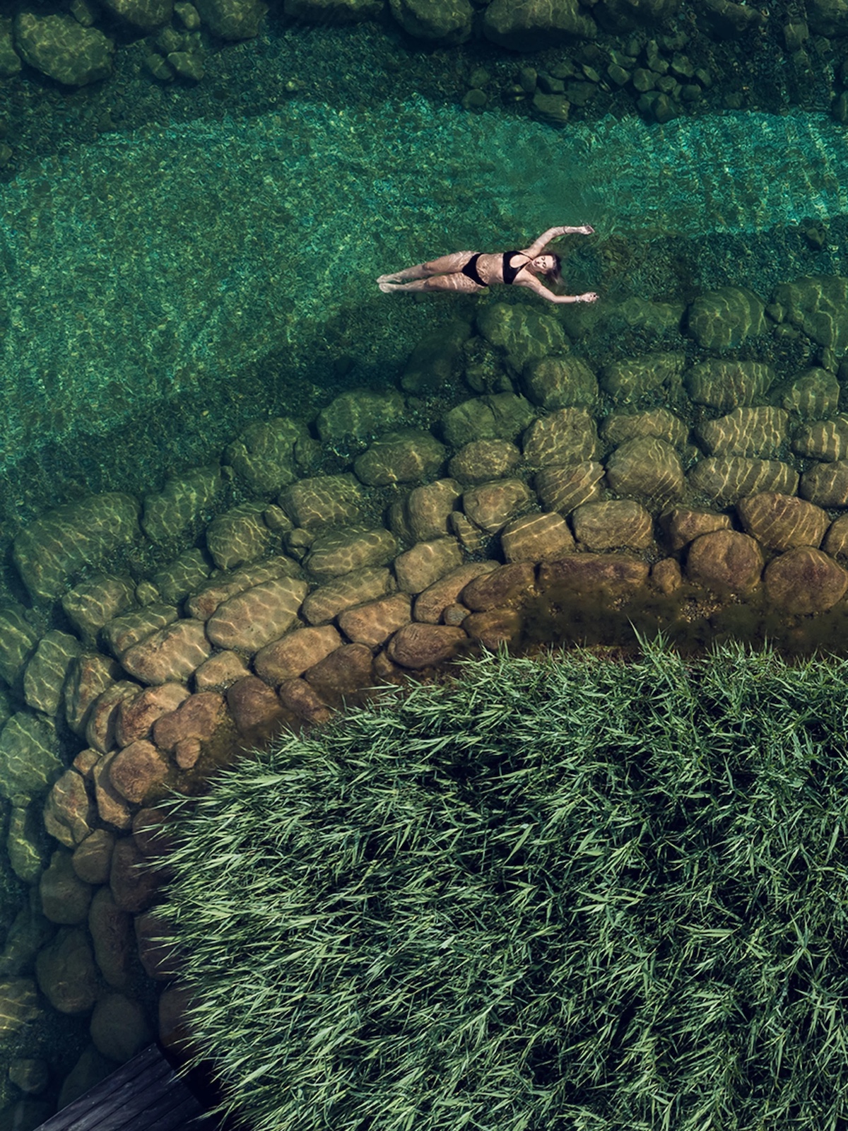 Birds eye photo of person swiming in an outdoor fresh natruarl lake pool in emerald green colours | Engel Spa Austria: Wellness Retreat in the Austrian Alps with Design Soul