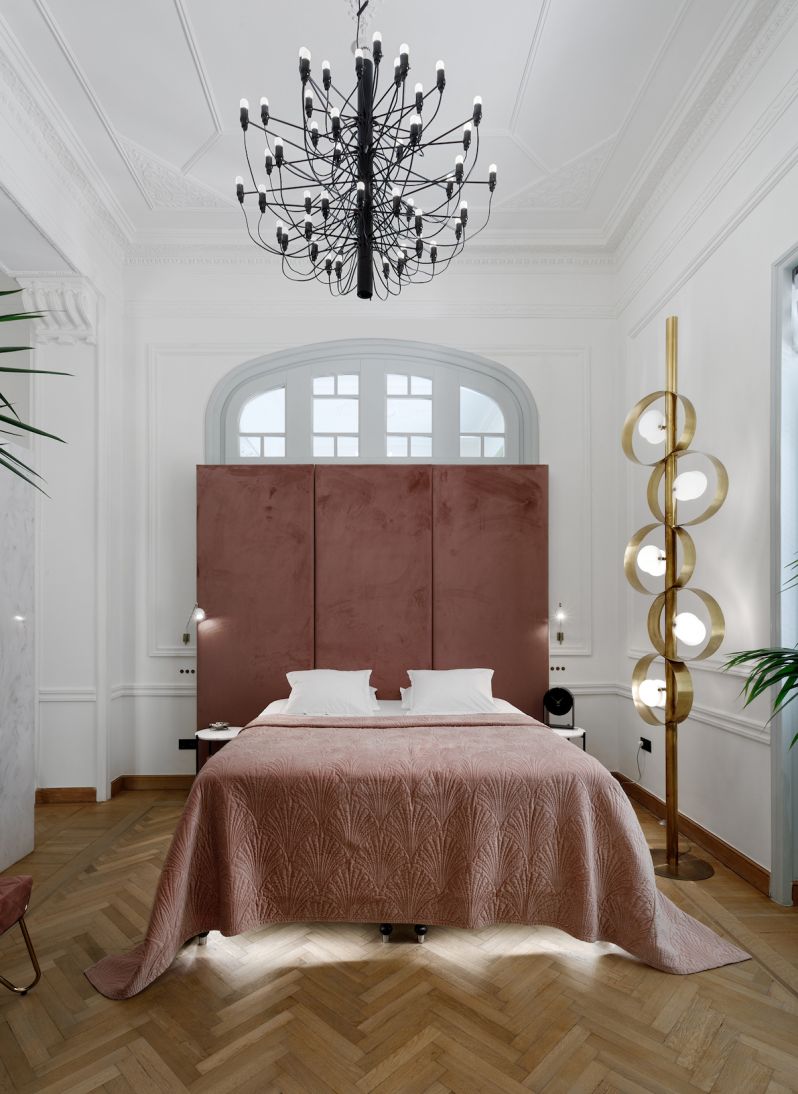 Pink bedroom concept of interiors, large central bed, matching headboard and quilt, statement designer lighting above the bed  wooden floors. | Aristides Hotel Syros Greece | The Art of Desking: Stylish Hotels for Work, Rest & Play – The Aficionados