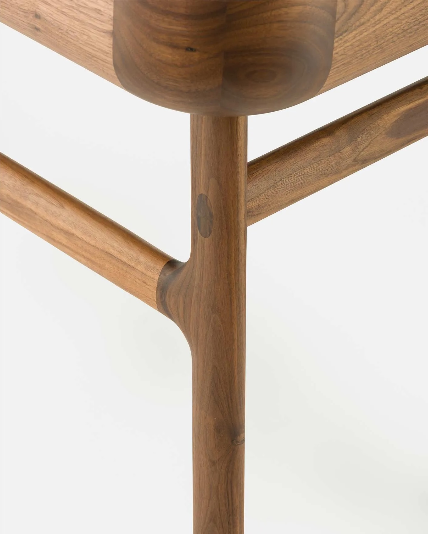 Close detail of the curved leg and stretcher joinery on a solid walnut table by De La Espada | The Aficionados