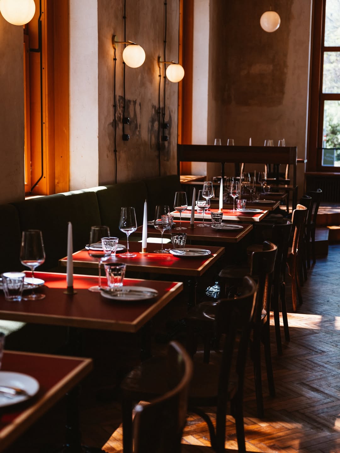 Late afternoon light across candlelit tables and bentwood chairs in the Donauhof dining room