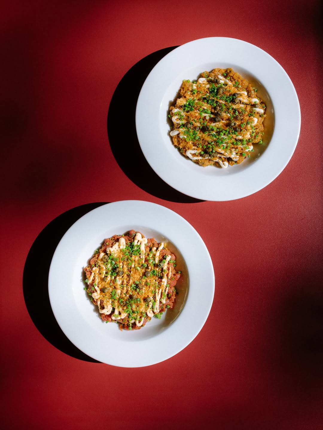 Two plates of beef tartare with capers, chives and crisp topping at Donauhof, Vienna